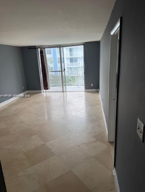 An empty room with light-colored tile flooring, gray walls, and a sliding glass balcony door — 488 NW 165th St Rd # 408, Miami FL 33169, MIAMI, FL