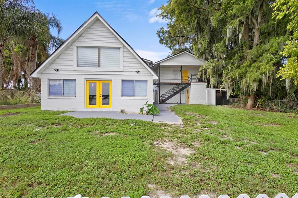 A white two-story house with yellow doors and an exterior staircase sits on a lawn — 1824 LAKE STREET, OVIEDO, FL
