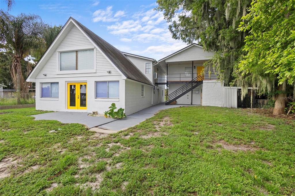 A two-story white house features yellow doors, a metal staircase, and a concrete patio — 1824 LAKE STREET, OVIEDO, FL