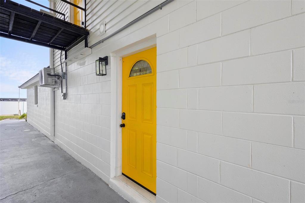 A bright yellow door is set into a white concrete block exterior wall — 1824 LAKE STREET, OVIEDO, FL
