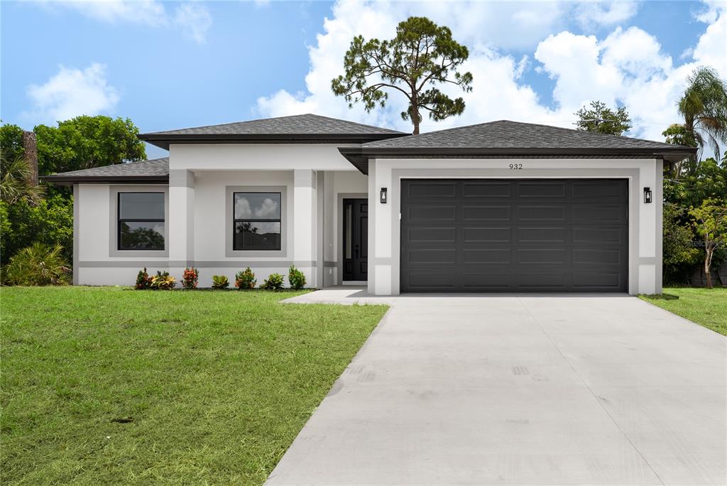 A modern single-story house with a white exterior, dark gray garage door, and concrete driveway — 923 CUMBERLAND ROAD, VENICE, FL