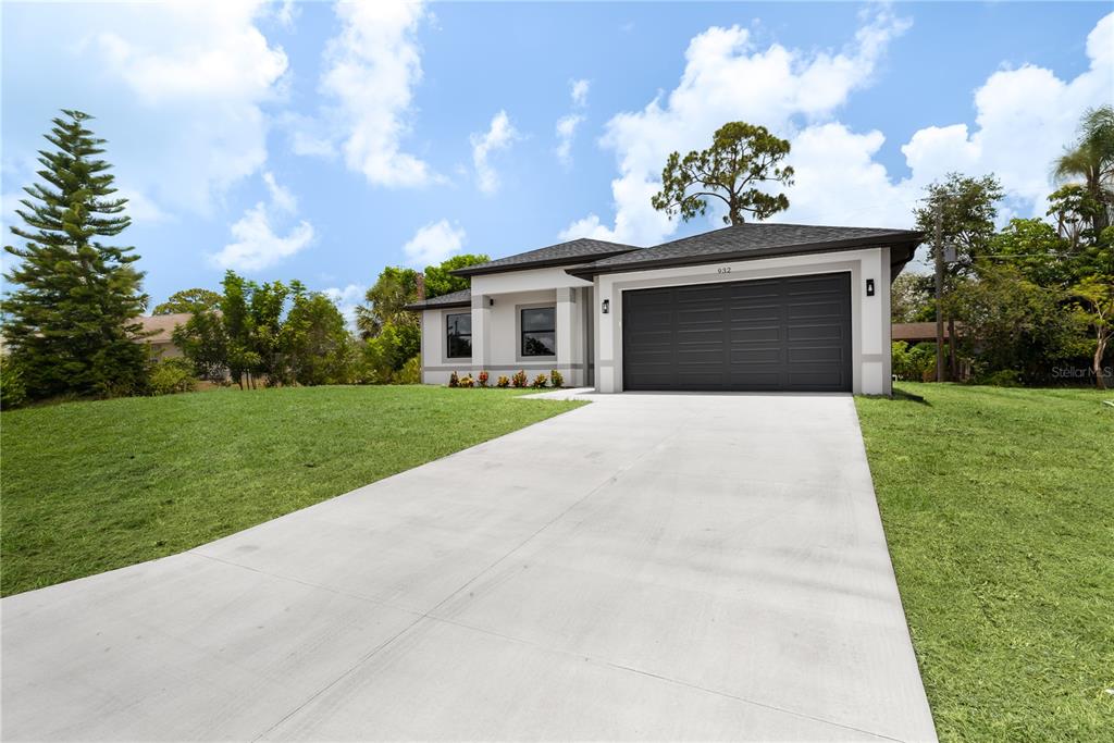 A single-story house with a gray garage door, white exterior, and a concrete driveway — 923 CUMBERLAND ROAD, VENICE, FL
