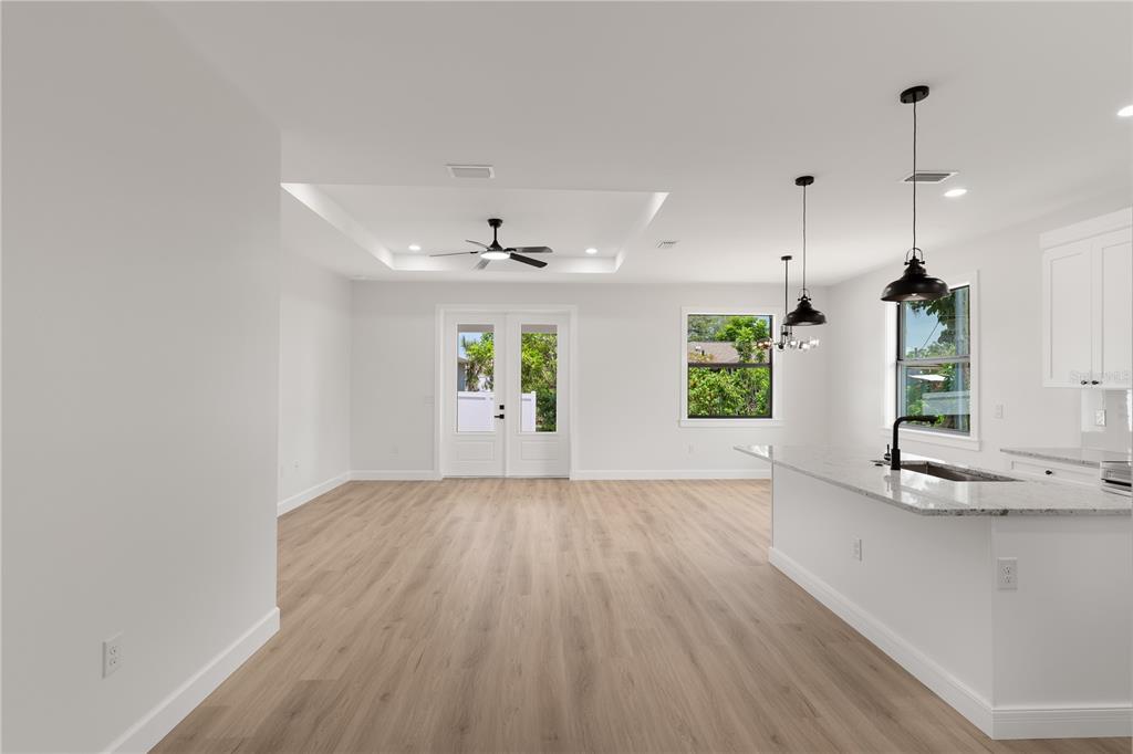 An open-concept living area with light wood flooring, a tray ceiling, and a kitchen island — 923 CUMBERLAND ROAD, VENICE, FL