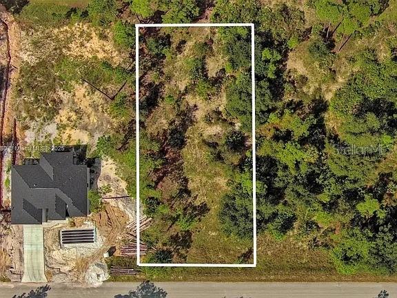 An aerial view shows a rectangular vacant lot outlined in white next to a house — 1219 WASHINGTON AVENUE, LEHIGH ACRES, FL