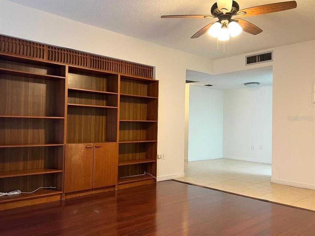 A room with dark wood flooring, a large built-in bookshelf, and a ceiling fan — 6039 VILLAGE CIRCLE BLDG C, ORLANDO, FL