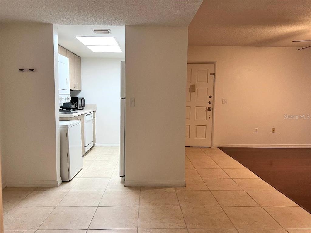 A tiled kitchen area is visible through an opening next to a white front door — 6039 VILLAGE CIRCLE BLDG C, ORLANDO, FL