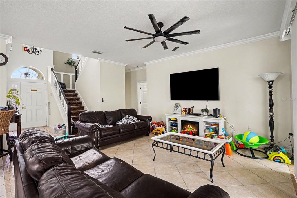A living room features brown leather sofas, a television, a fireplace console, and tile flooring — 615 COPELAND DRIVE, HAINES CITY, FL