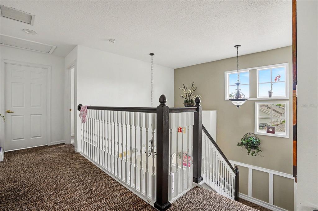 A carpeted landing features a wooden staircase railing and a view of a lower level — 615 COPELAND DRIVE, HAINES CITY, FL