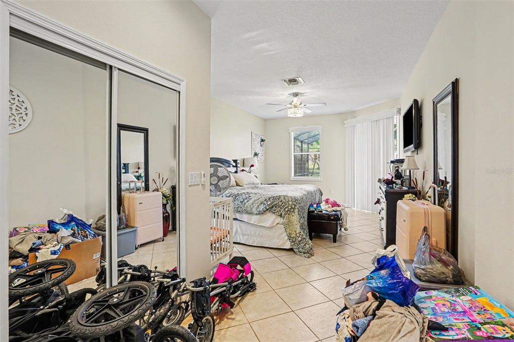 A bedroom with tile flooring, a bed, a ceiling fan, and mirrored closet doors — 615 COPELAND DRIVE, HAINES CITY, FL