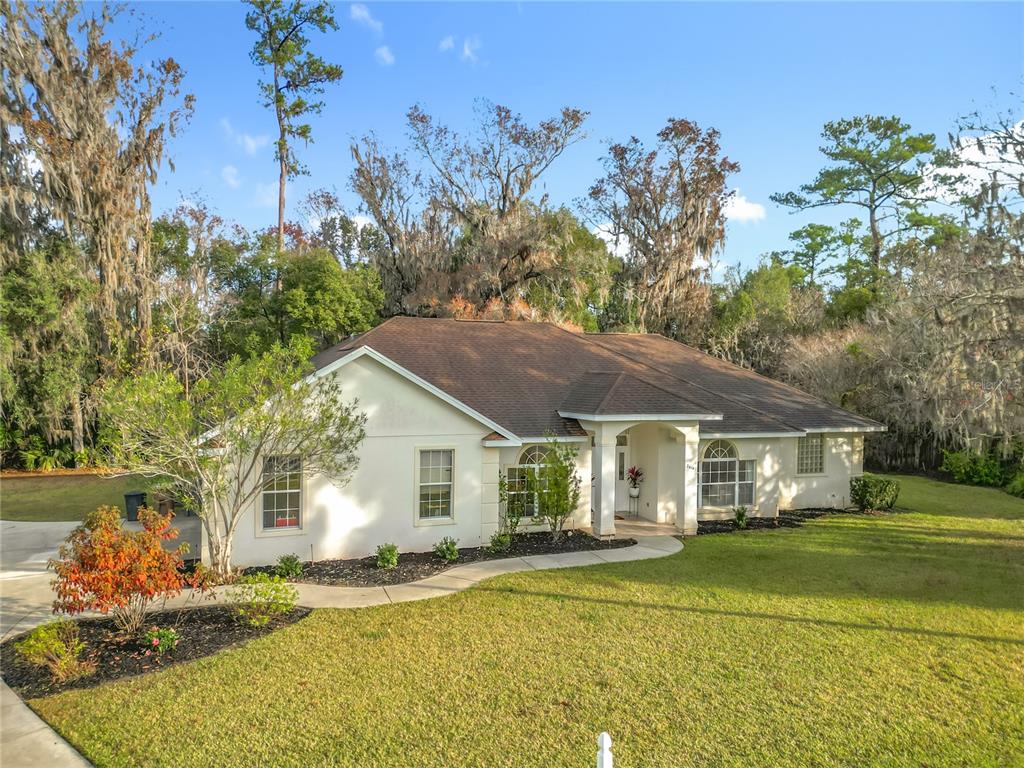 A single-story house with a light-colored exterior, brown roof, and a curved walkway — 2614 SE 25TH COURT, OCALA, FL