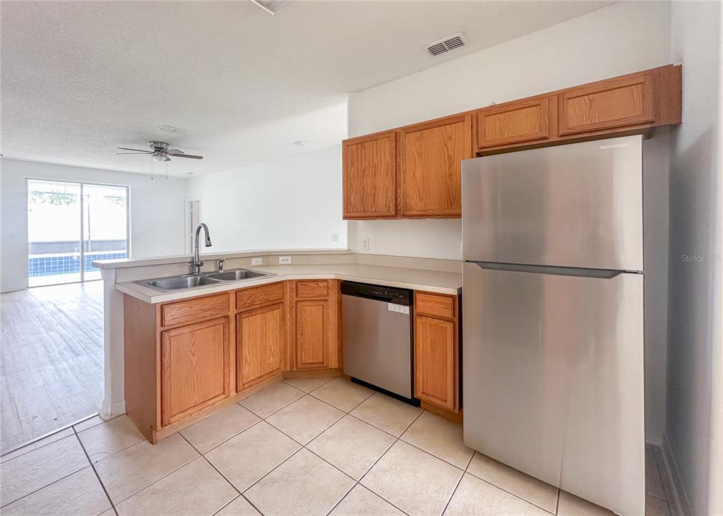 A kitchen features oak cabinets, stainless steel appliances, and tile flooring — 402 SUNSET VIEW DRIVE, DAVENPORT, FL