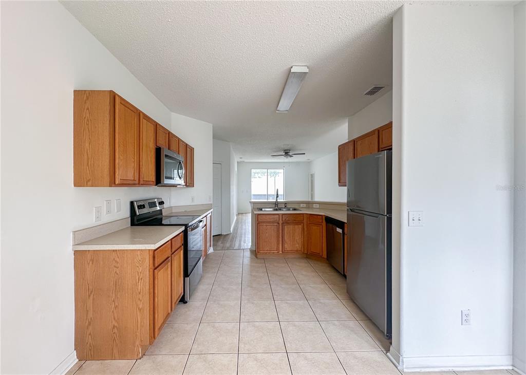 A kitchen features wood cabinets, stainless steel appliances, and tile flooring — 402 SUNSET VIEW DRIVE, DAVENPORT, FL
