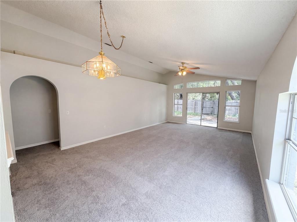A spacious living room features gray carpeting, a vaulted ceiling, and sliding glass patio doors — 114 PAMALA COURT, SANFORD, FL