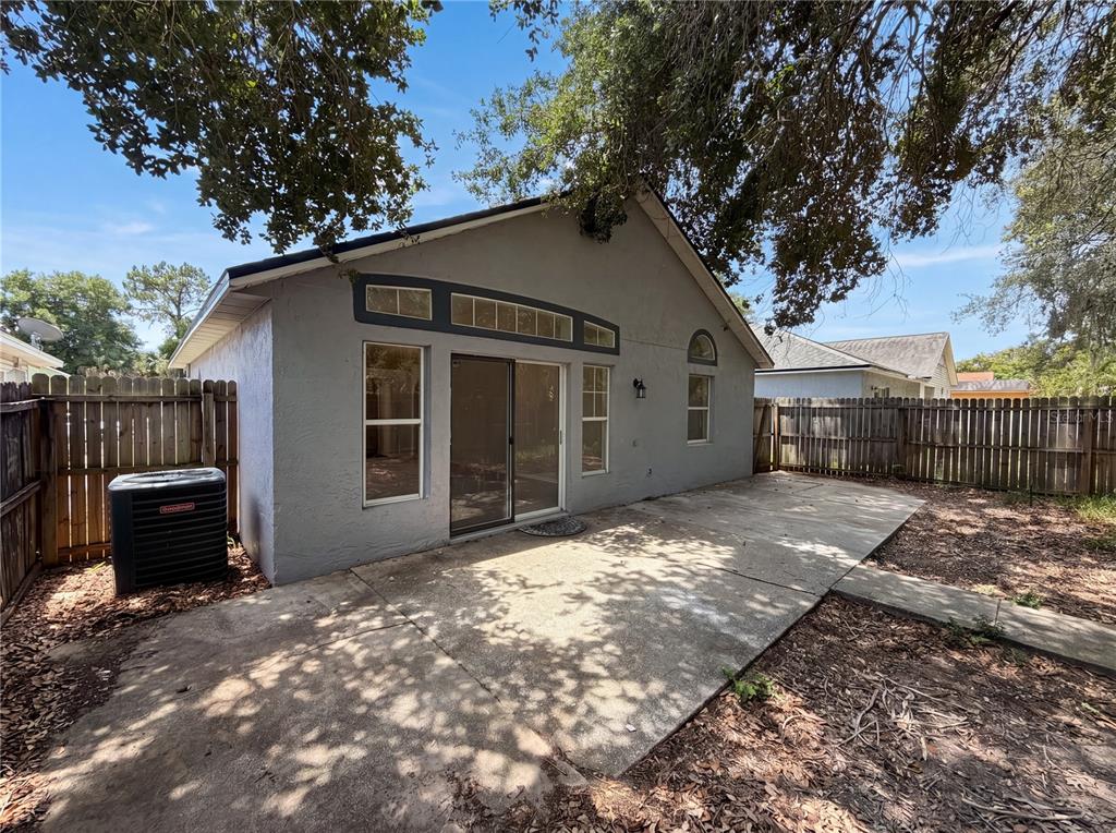 A gray house exterior features a concrete patio, sliding glass doors, and a wooden fence — 114 PAMALA COURT, SANFORD, FL