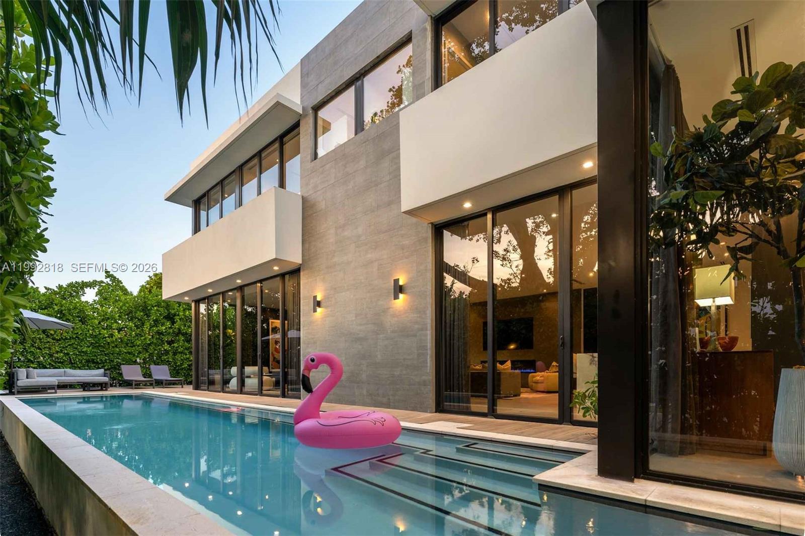 A modern two-story house exterior features a swimming pool with a pink flamingo float — 121 2nd Dilido Ter. Share A, Miami Beach FL 33139, MIAMI BEACH, FL