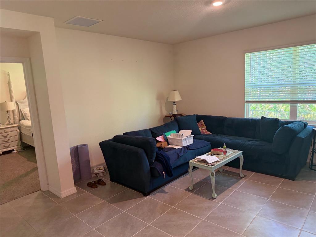 A living room features a large blue sectional sofa, a coffee table, and tile flooring — 1339 MORNING WALK DRIVE, ORMOND BEACH, FL