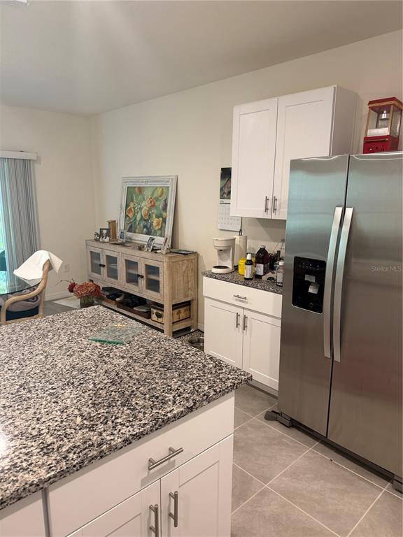 A kitchen features white cabinets, granite countertops, a stainless steel refrigerator, and a wooden sideboard — 1339 MORNING WALK DRIVE, ORMOND BEACH, FL