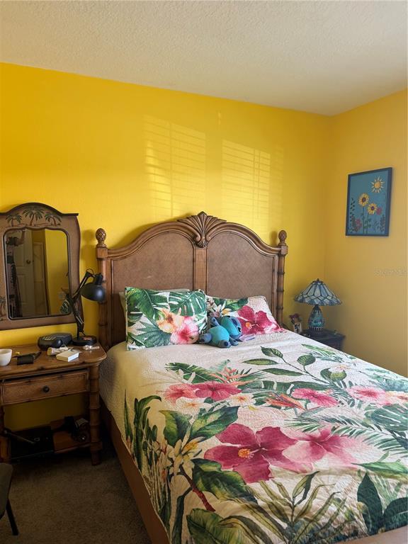 A bedroom features a wooden bed with a floral quilt, yellow walls, and a vanity mirror — 1339 MORNING WALK DRIVE, ORMOND BEACH, FL