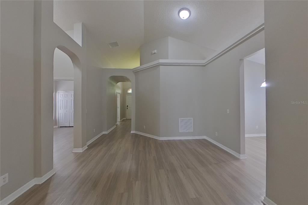 An interior view of a hallway and entryway with light wood-look flooring and arched doorways — 2143 KAYLAS COURT, ORLANDO, FL
