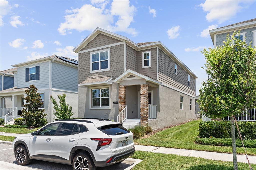 A two-story house with tan siding and stone accents features a white SUV parked outside — 2999 ADDISON BOULEVARD, ST CLOUD, FL