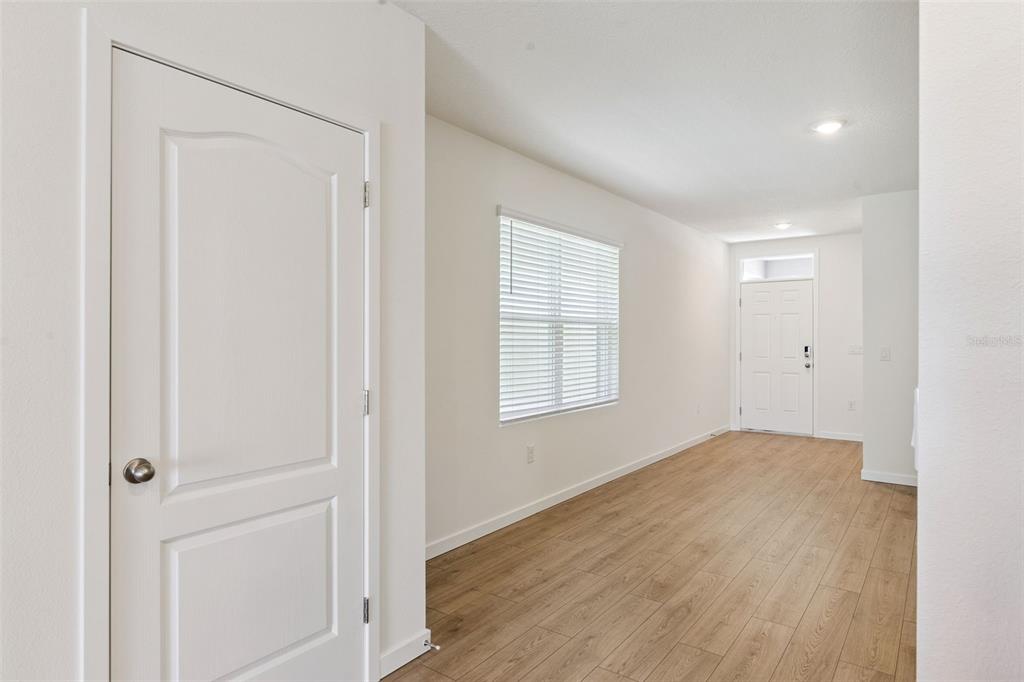 An interior view shows a room with light wood-look flooring, white walls, and a window — 2344 BAYWOOD FLOWER WAY, OCOEE, FL