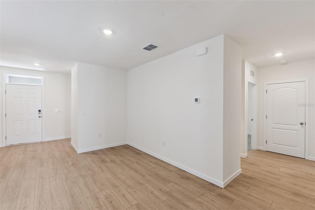 An interior view shows a white-walled room with light wood-look flooring and two doors — 2344 BAYWOOD FLOWER WAY, OCOEE, FL