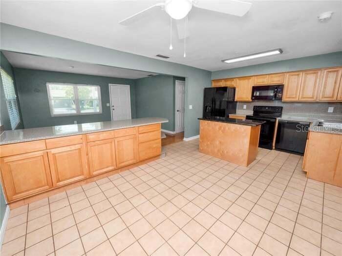 A kitchen features light wood cabinets, a central island, and tile flooring — 5134 W HARVARD STREET W, LAKELAND, FL