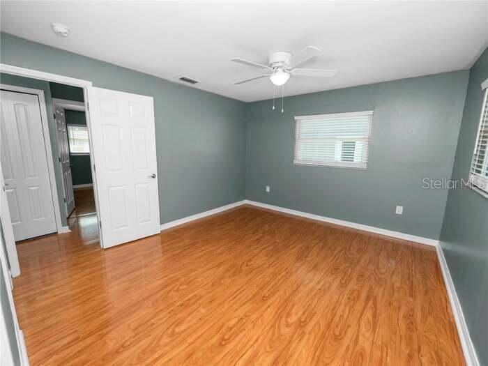 An empty bedroom features blue-gray walls, wood-look laminate flooring, a ceiling fan, and white trim — 5134 W HARVARD STREET W, LAKELAND, FL