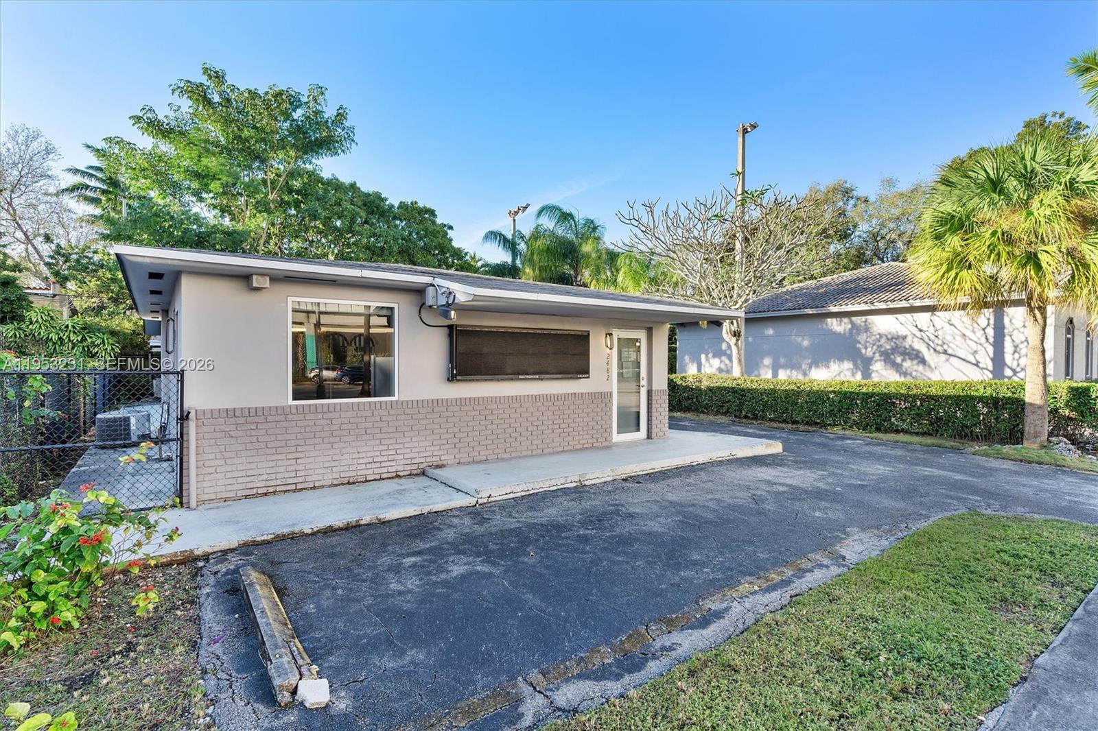 A single-story commercial building with a gray brick facade, a glass door, and asphalt parking — 2482 SW Secoffee Ter, Miami FL 33133, MIAMI, FL