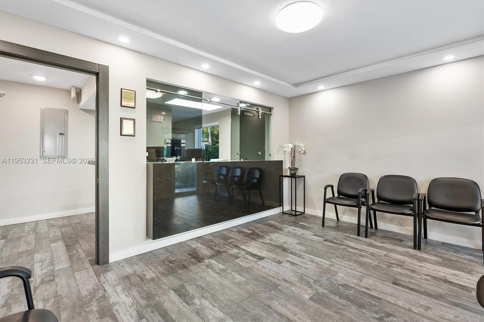 A waiting room features a reception desk, gray wood-look flooring, and three black chairs — 2482 SW Secoffee Ter, Miami FL 33133, MIAMI, FL