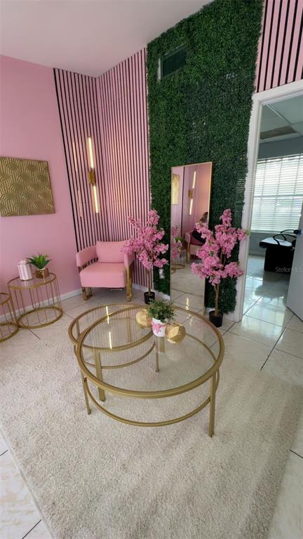 A pink-walled room features a green wall panel, a glass coffee table, and a pink chair — 318 N JOHN YOUNG PARKWAY UNIT 103, KISSIMMEE, FL