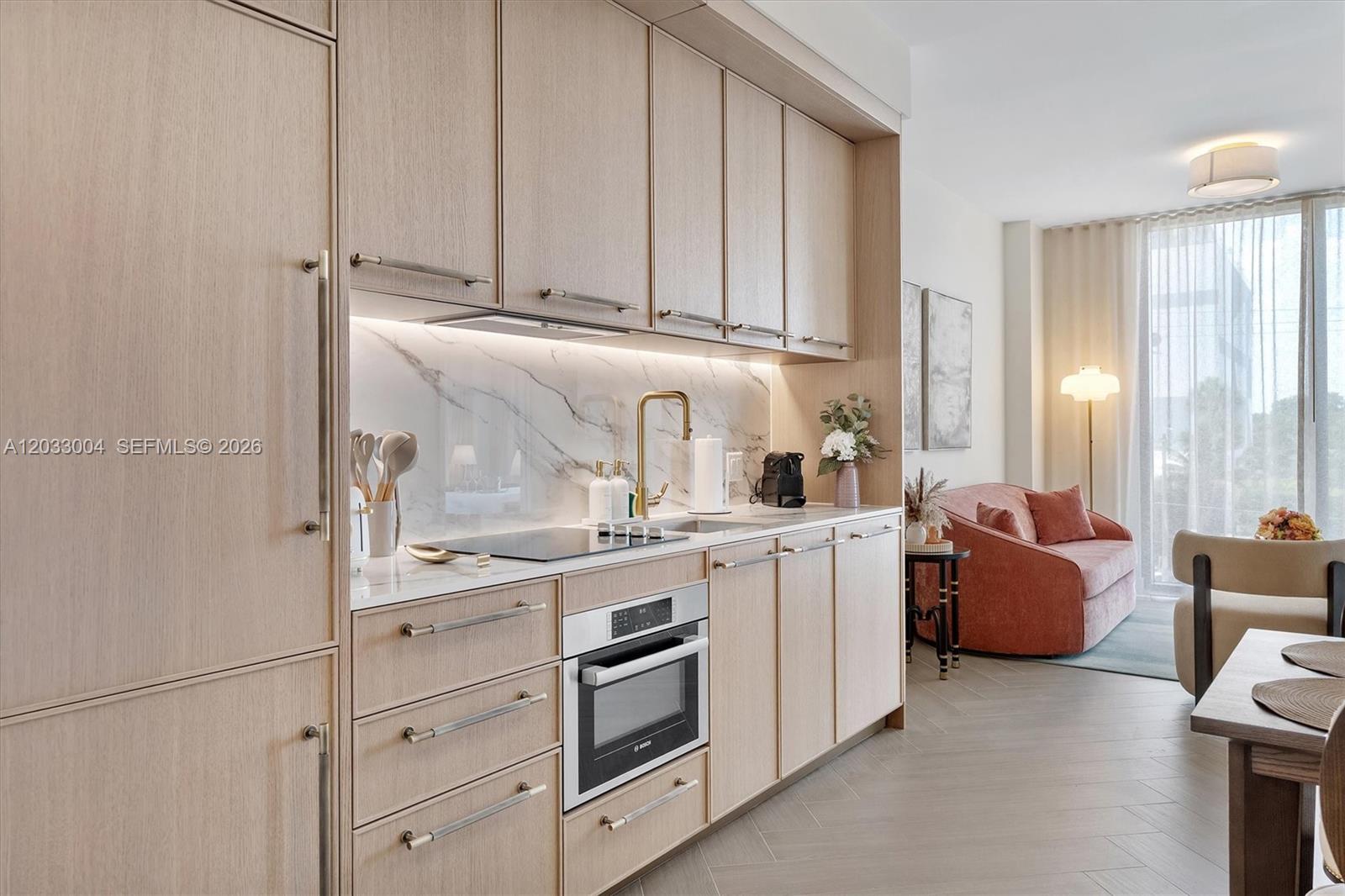 A modern kitchen features light wood cabinets, marble backsplash, and integrated appliances in an open layout — 2700 NW 2nd Ave # 230, Miami FL 33127, MIAMI, FL