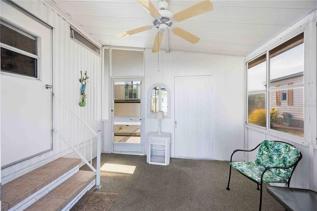 A sunroom with white walls, a ceiling fan, carpeted flooring, and a single patterned chair — 16 N GRANADA PLAZA, ENGLEWOOD, FL