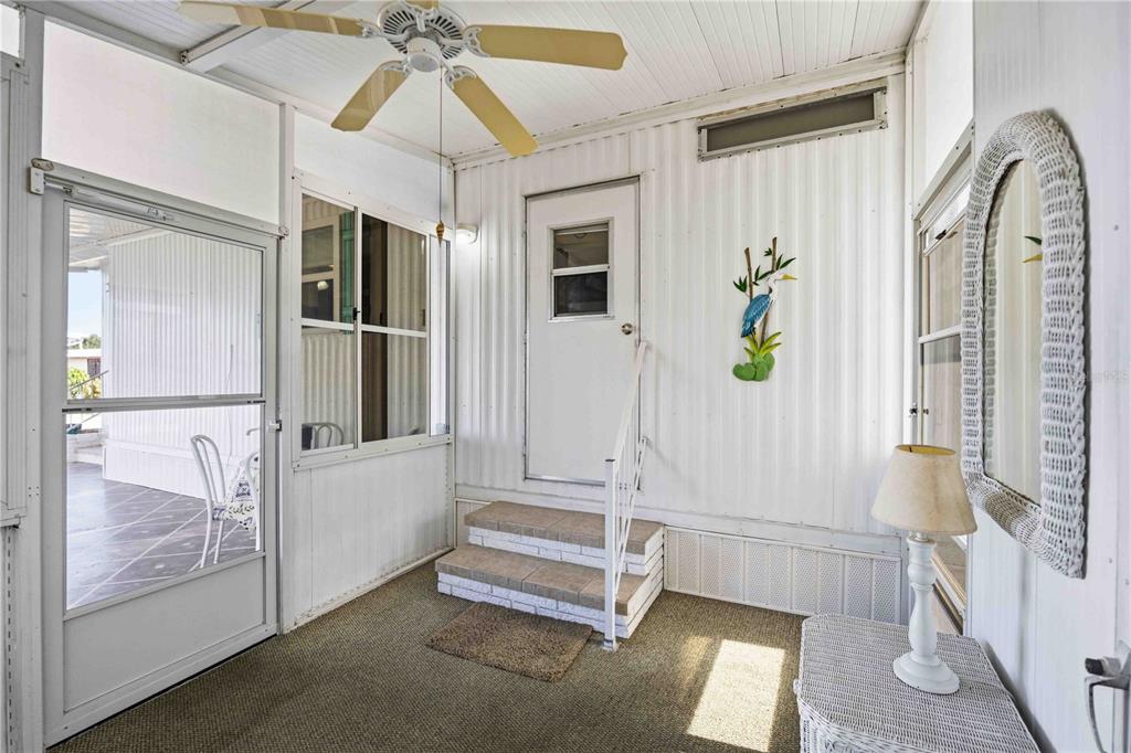 A sunroom features a ceiling fan, a white door with steps, and a wall-mounted heron decoration — 16 N GRANADA PLAZA, ENGLEWOOD, FL