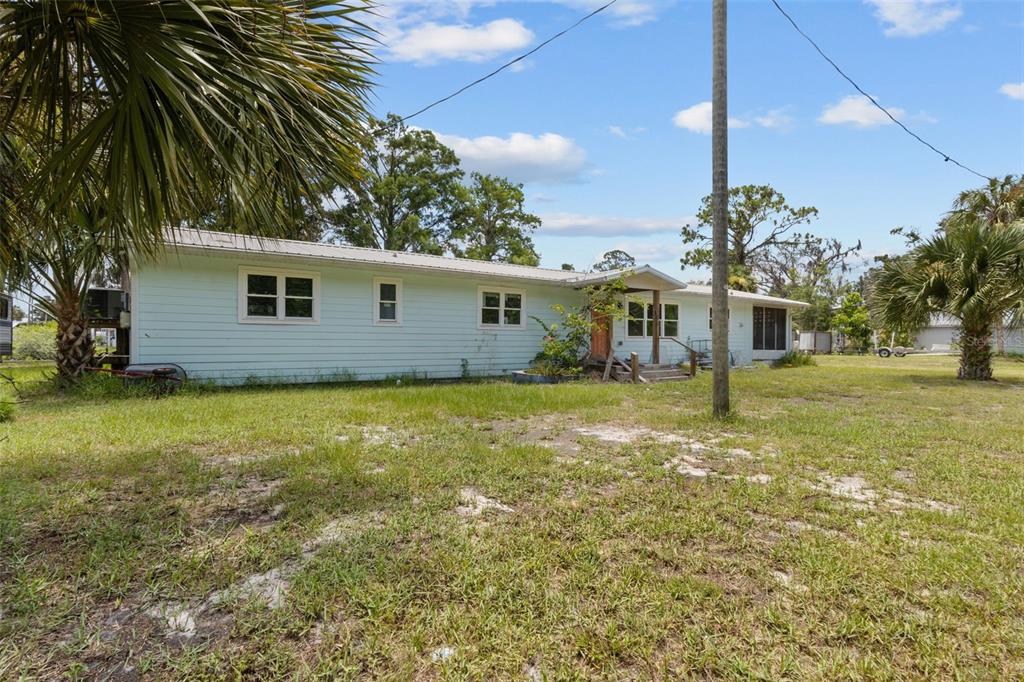 A light blue single-story house with a metal roof sits on a grassy lot — 306 SE 256 STREET, SUWANNEE, FL