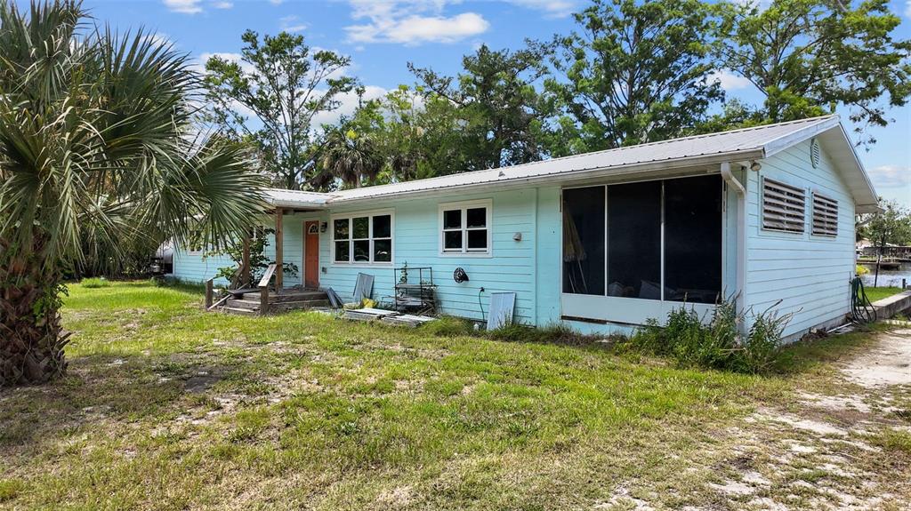 A light blue, single-story house with a metal roof and a screened-in porch — 306 SE 256 STREET, SUWANNEE, FL