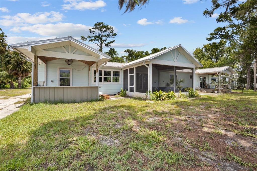 The exterior of a light blue house features a covered patio and a screened porch — 306 SE 256 STREET, SUWANNEE, FL