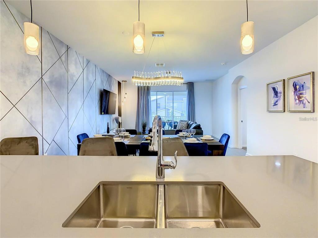 A kitchen sink overlooks a dining area with a geometric accent wall and chandelier — 8853 CABOT CLIFFS DRIVE UNIT 104, DAVENPORT, FL