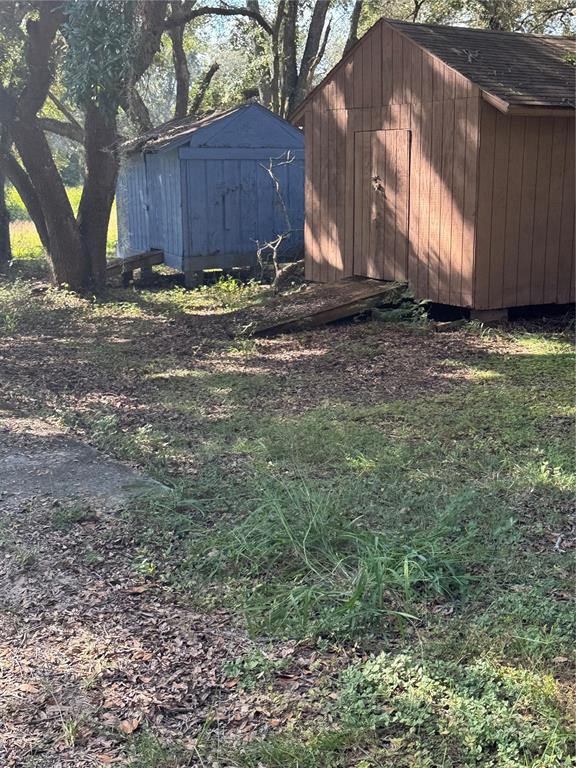 Two wooden sheds sit on a grassy, leaf-covered lot surrounded by trees — 2101 STATE ROAD 50, GROVELAND, FL