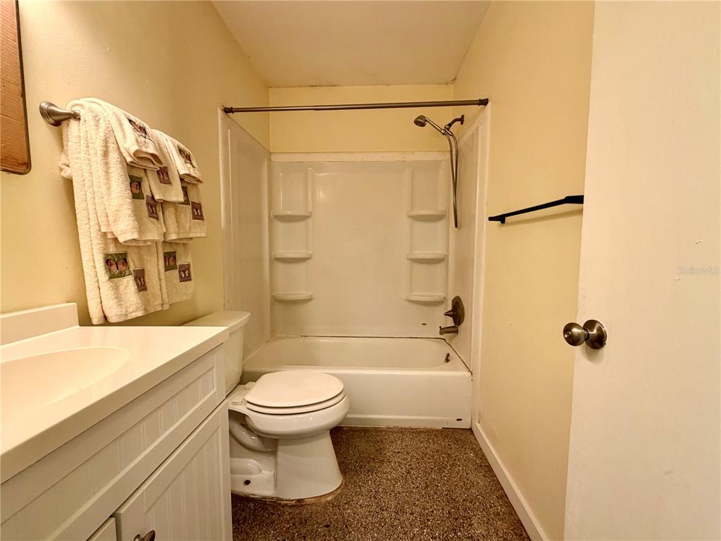 A bathroom features a white vanity, a toilet, and a shower-tub combination with beige walls — 513 AVENUE J SE, WINTER HAVEN, FL