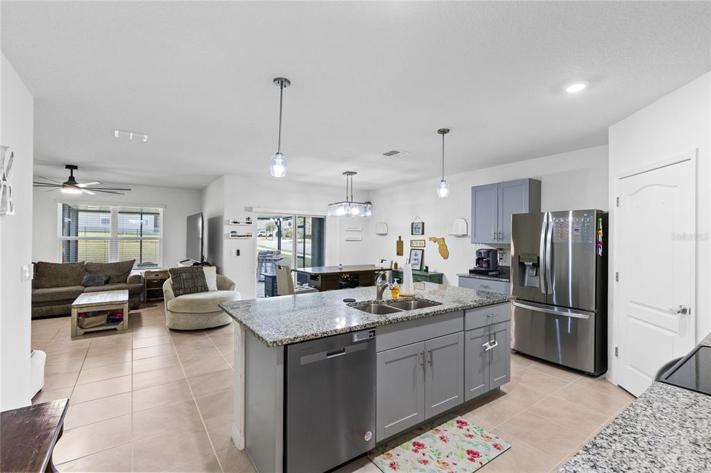 A kitchen with a granite-topped island and gray cabinets opens into a living area — 452 BARONESS WAY, DELAND, FL