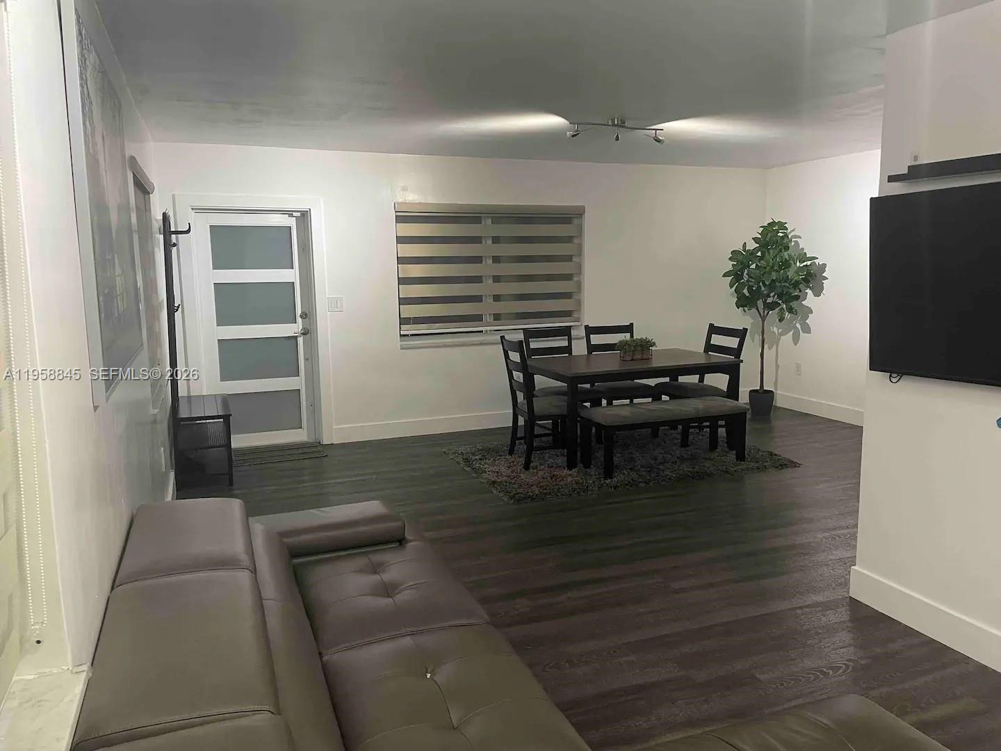 A living and dining area features dark wood-look flooring, white walls, and modern furniture — 3008 NW 13th St, Miami FL 33125, MIAMI, FL