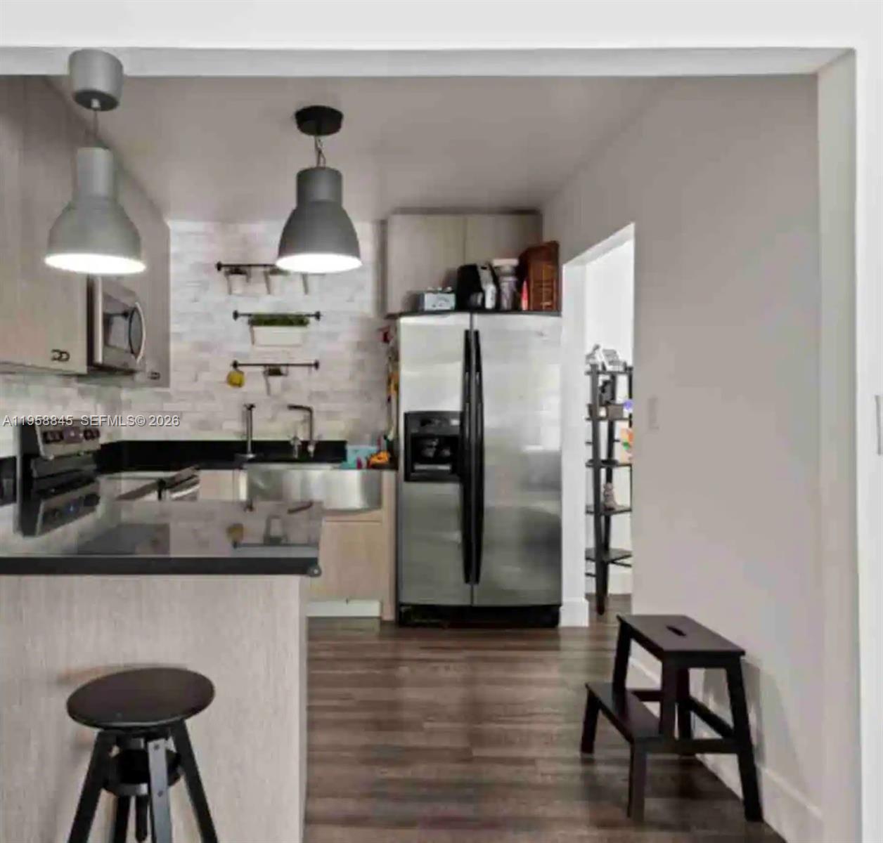 A kitchen features stainless steel appliances, dark countertops, light wood cabinets, and two pendant lights — 3008 NW 13th St, Miami FL 33125, MIAMI, FL