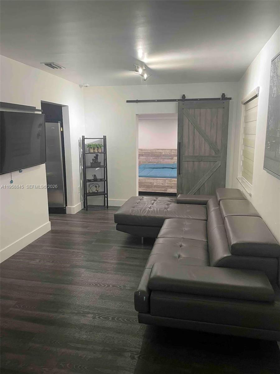 A living room features dark wood-look flooring, a grey sectional sofa, and a sliding barn door — 3008 NW 13th St, Miami FL 33125, MIAMI, FL