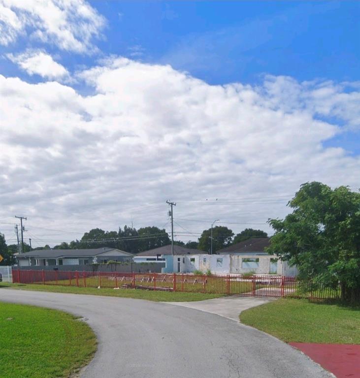 A fenced, vacant residential lot features a partially demolished house structure under a cloudy sky — 21710 SW 111TH AVENUE, MIAMI, FL