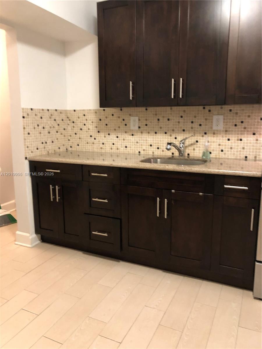 A kitchen features dark wood cabinets, granite countertops, and a beige mosaic tile backsplash — 221 SW 9 AVE # 2, Miami FL 33130, MIAMI, FL