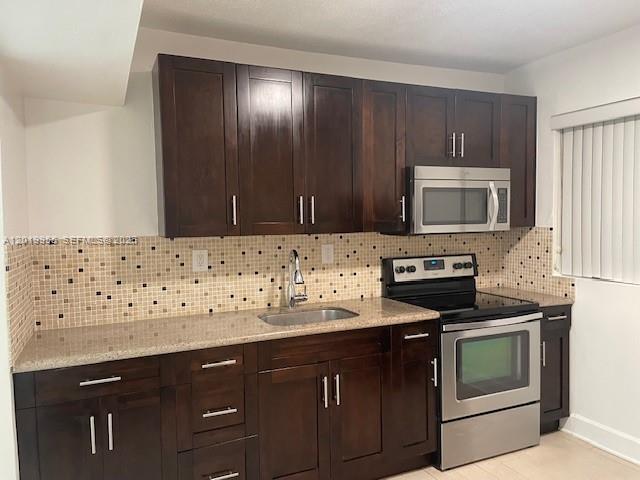 A kitchen features dark wood cabinets, stainless steel appliances, and a tan mosaic tile backsplash — 221 SW 9 AVE # 2, Miami FL 33130, MIAMI, FL