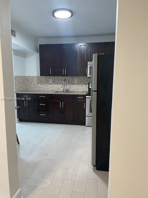 A kitchen features dark wood cabinets, light-colored tile flooring, and a stainless steel refrigerator — 221 SW 9 AVE # 2, Miami FL 33130, MIAMI, FL