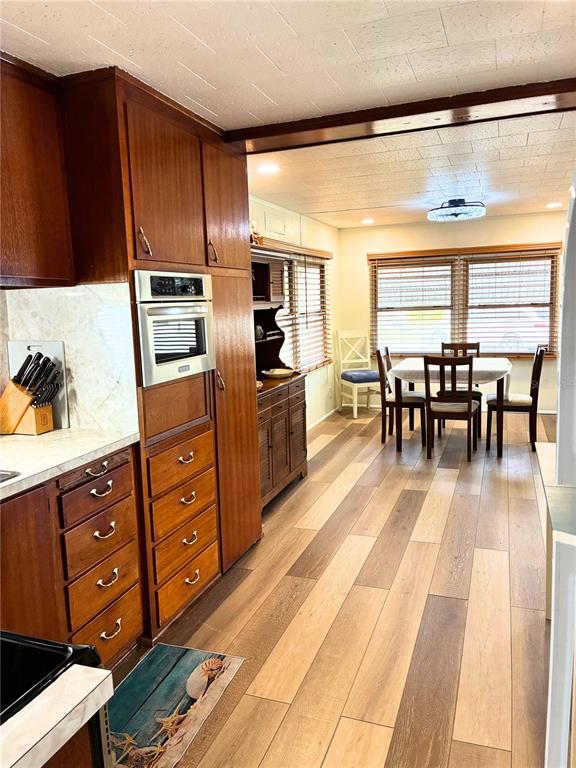 A kitchen with wood cabinets and a built-in oven connects to a dining area — 4981 PEBBLE BEACH AVENUE, SARASOTA, FL