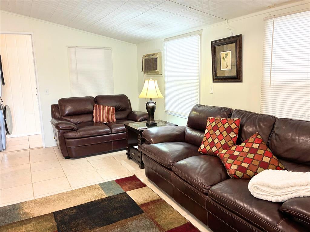 A living room features two brown leather sofas, a patterned area rug, and tile flooring — 4981 PEBBLE BEACH AVENUE, SARASOTA, FL